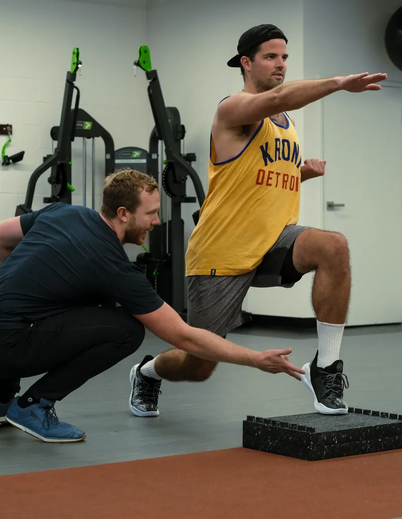 A coach cues a client's squat depth and form